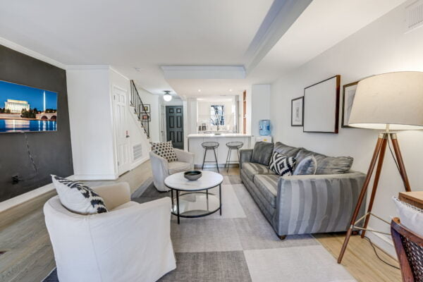 Living room with open concept kitchen, front entrance, sleeper sofa, and 55" Samsung TV.